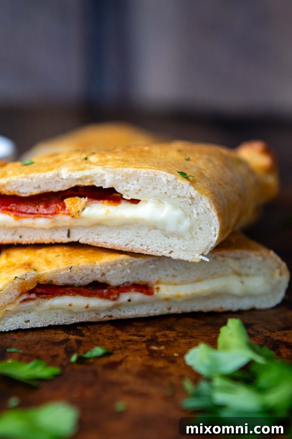 A perfectly baked, golden-brown gluten-free calzone, expertly sliced open to reveal a luscious, molten stream of cheese oozing out, surrounded by savory fillings.