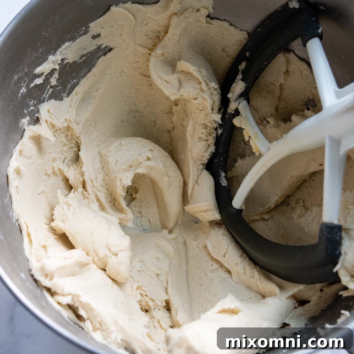 Freshly mixed gluten-free calzone dough in a white mixing bowl, displaying a slightly sticky but firm consistency.