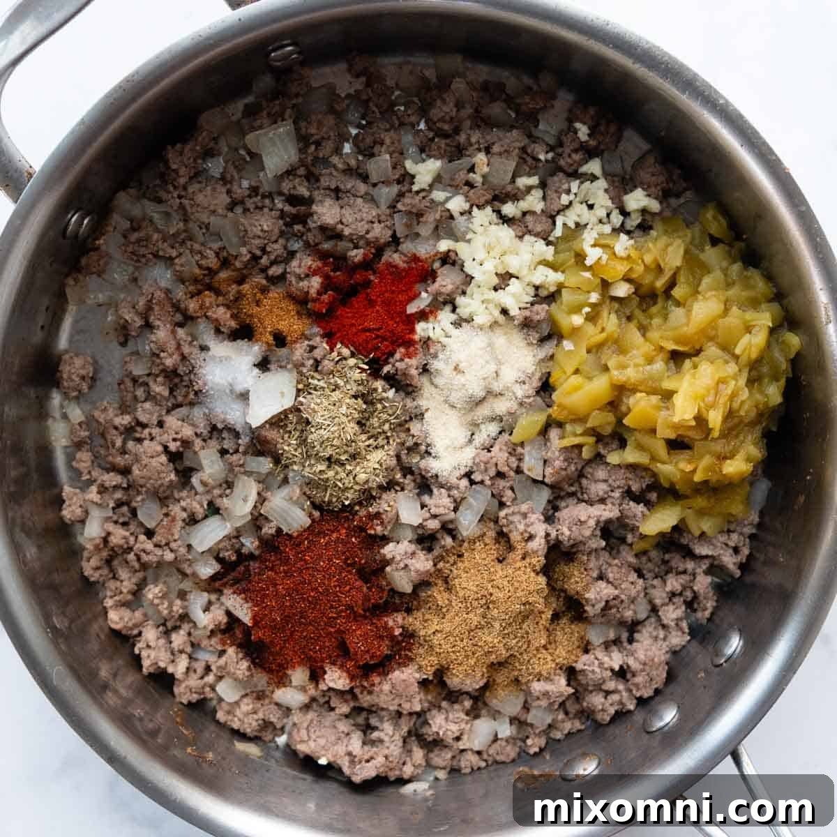 Beef and seasonings in a skillet.