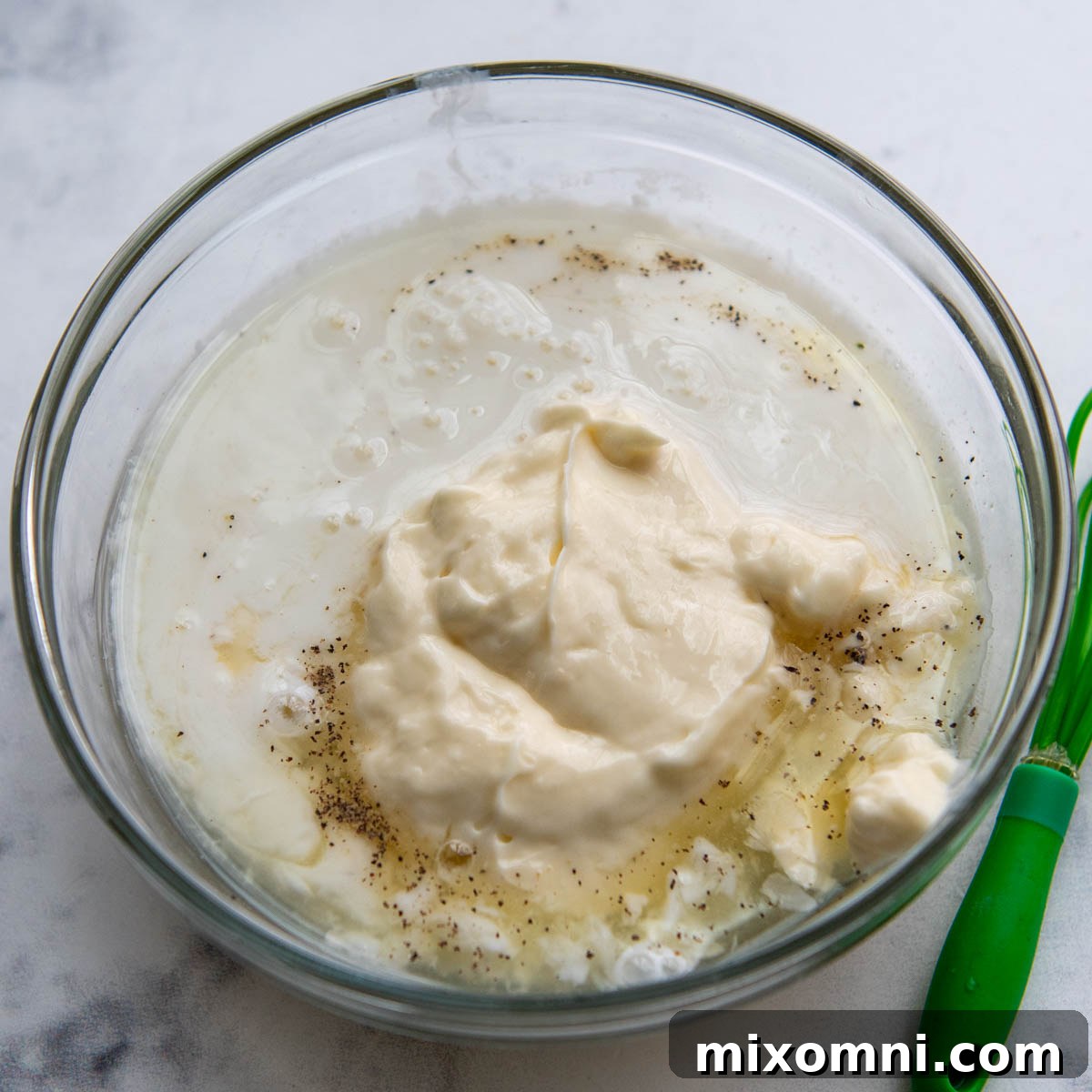 Close-up of creamy coleslaw dressing in a bowl, ready to be combined with the slaw mixture.
