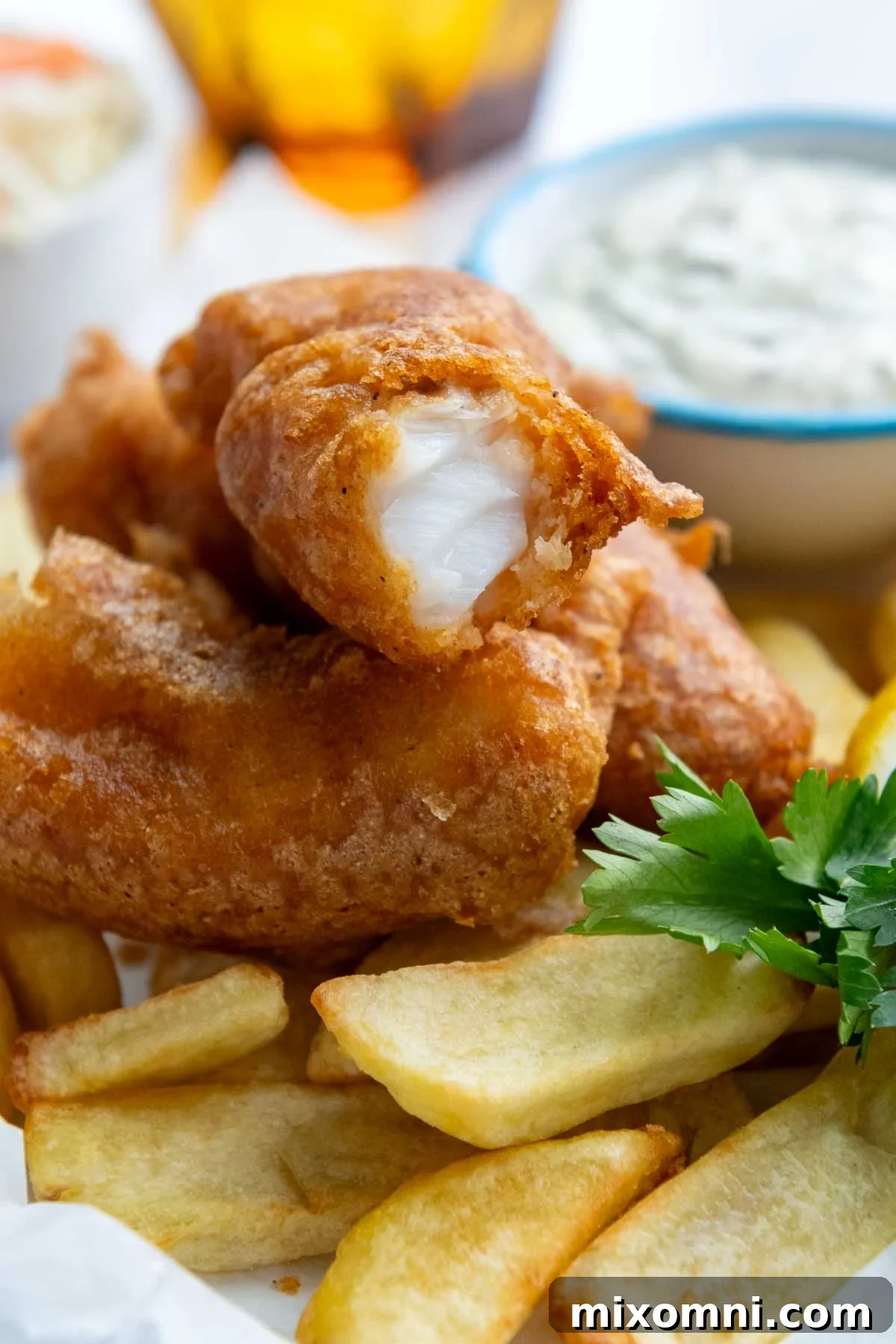 A generous serving of golden, crispy fried fish resting atop a mound of perfectly cooked french fries, ready to be enjoyed.