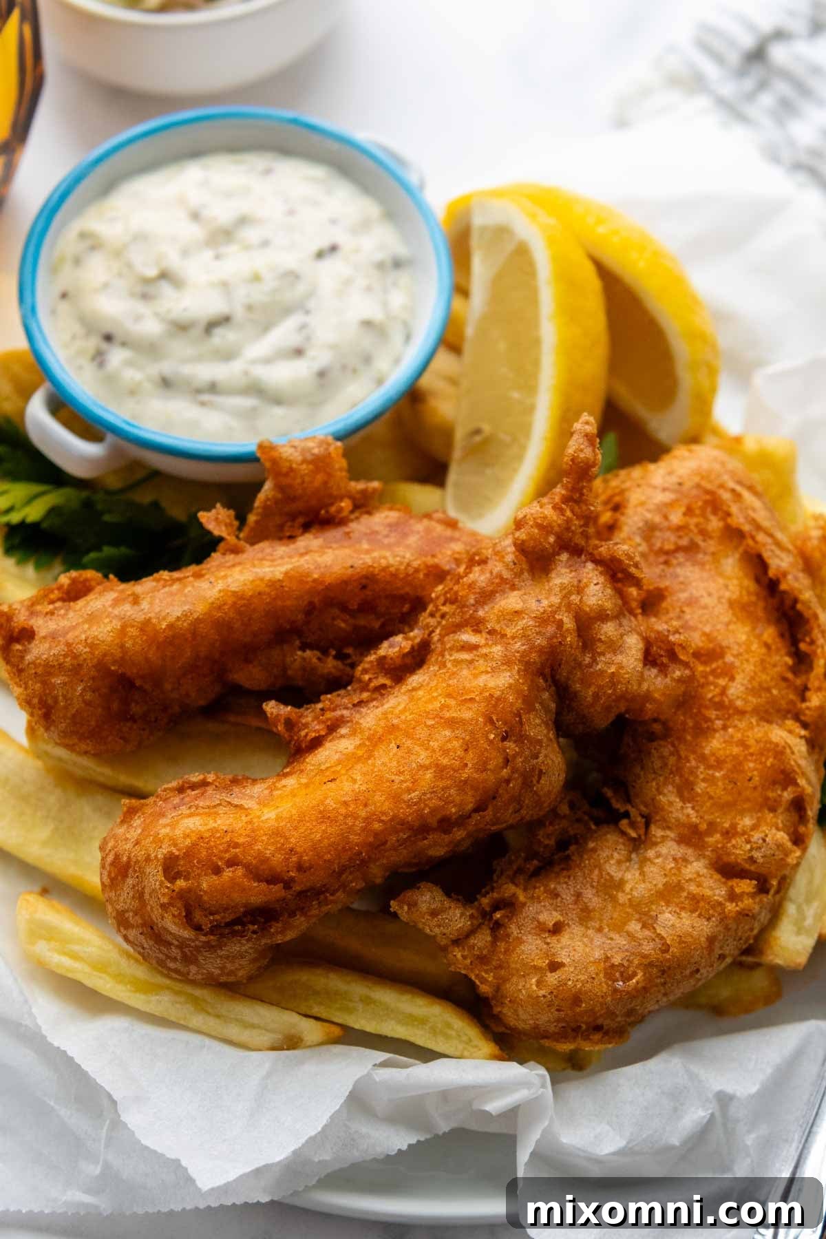 A delectable serving of pub-style fried fish and chips, accompanied by a side of creamy tartar sauce and fresh lemon wedges, ready for a gluten-free feast.