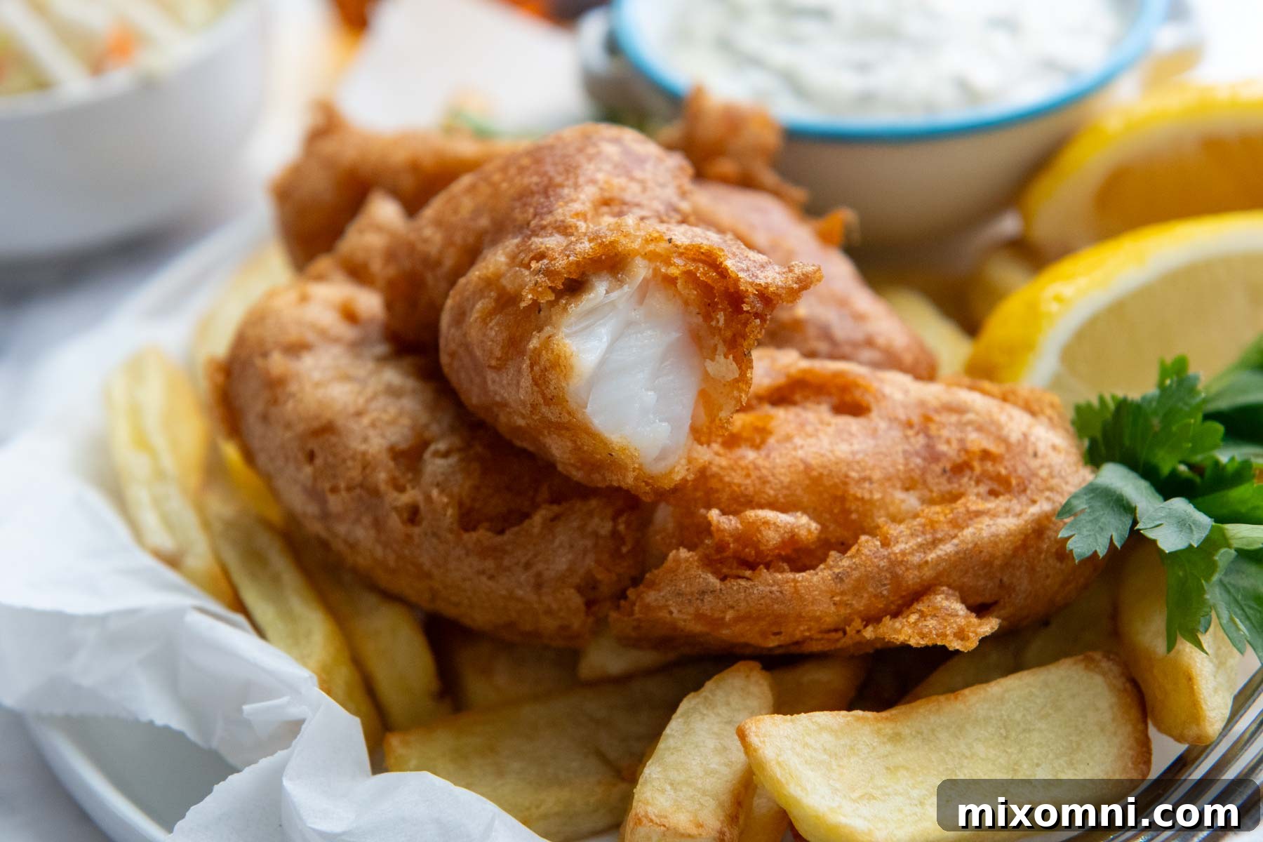 A close-up shot of a crispy piece of gluten-free fried fish, with a bite taken out, resting on a bed of french fries, tempting with its golden perfection.