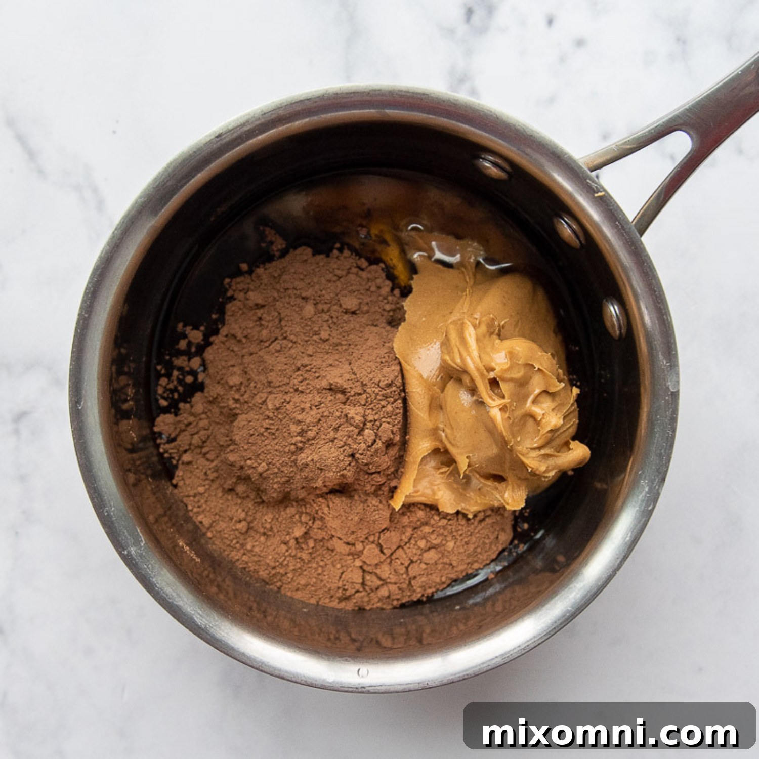 Chocolate peanut butter mixture bubbling gently in a saucepan, looking smooth and glossy.