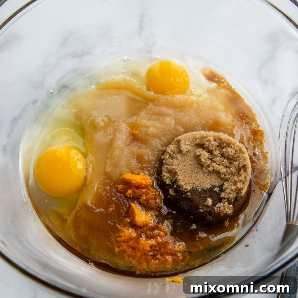 the eggs in a glass bowl with other wet ingredients ready to be whisked.