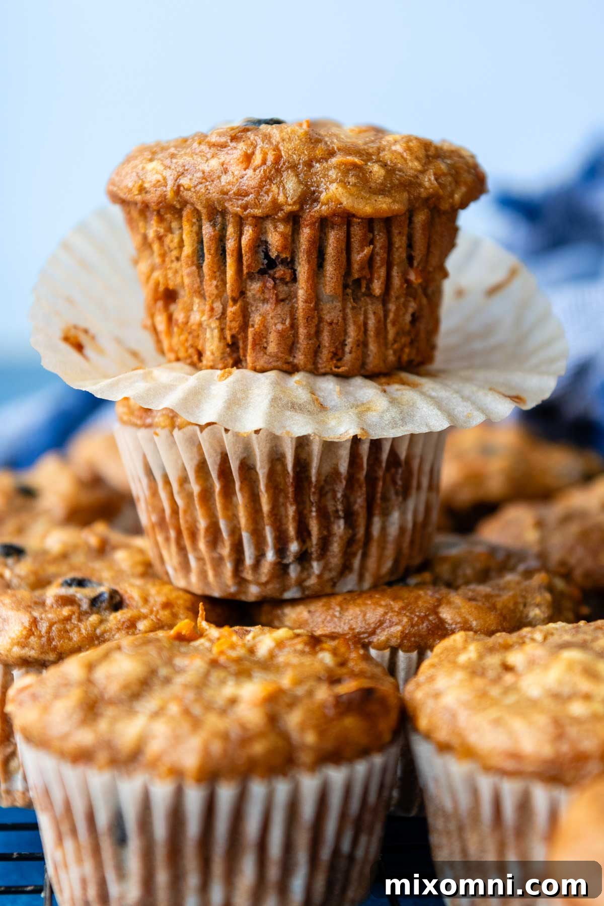 a stack of two golden-brown carrot muffins with the paper liners removed, showing a tender interior.