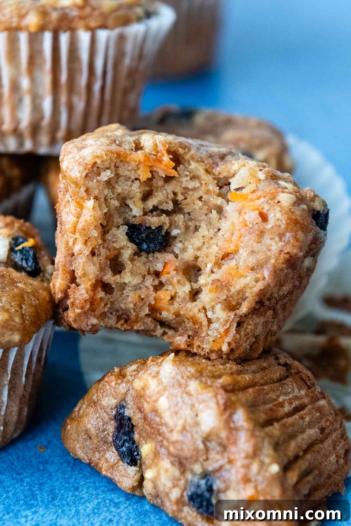 a muffin with a bite taken out, stacked on other moist, gluten-free morning glory muffins.