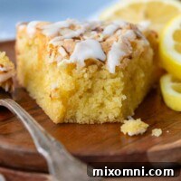 a slice of cake facing camera with a bite taken out and lemons on the plate.