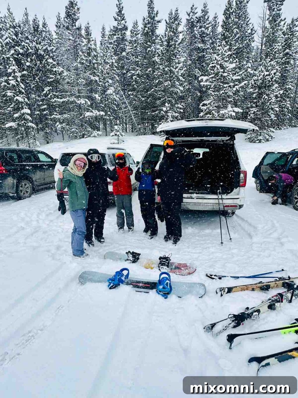Family getting ready to ski, posing by their car in a snowy parking lot.