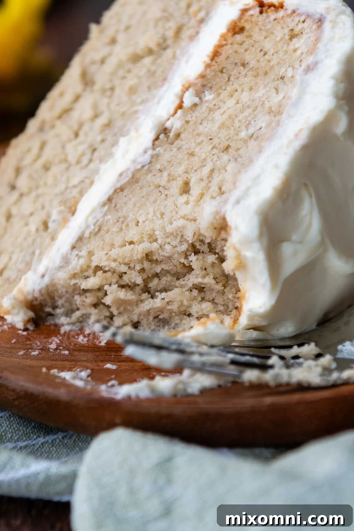 A perfectly sliced piece of fluffy gluten-free banana cake, showing its moist crumb and creamy frosting, with a bite taken out.