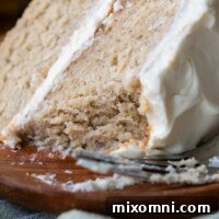 A slice of gluten free banana cake with a bite taken out, showing the fluffy crumb and cream cheese frosting.