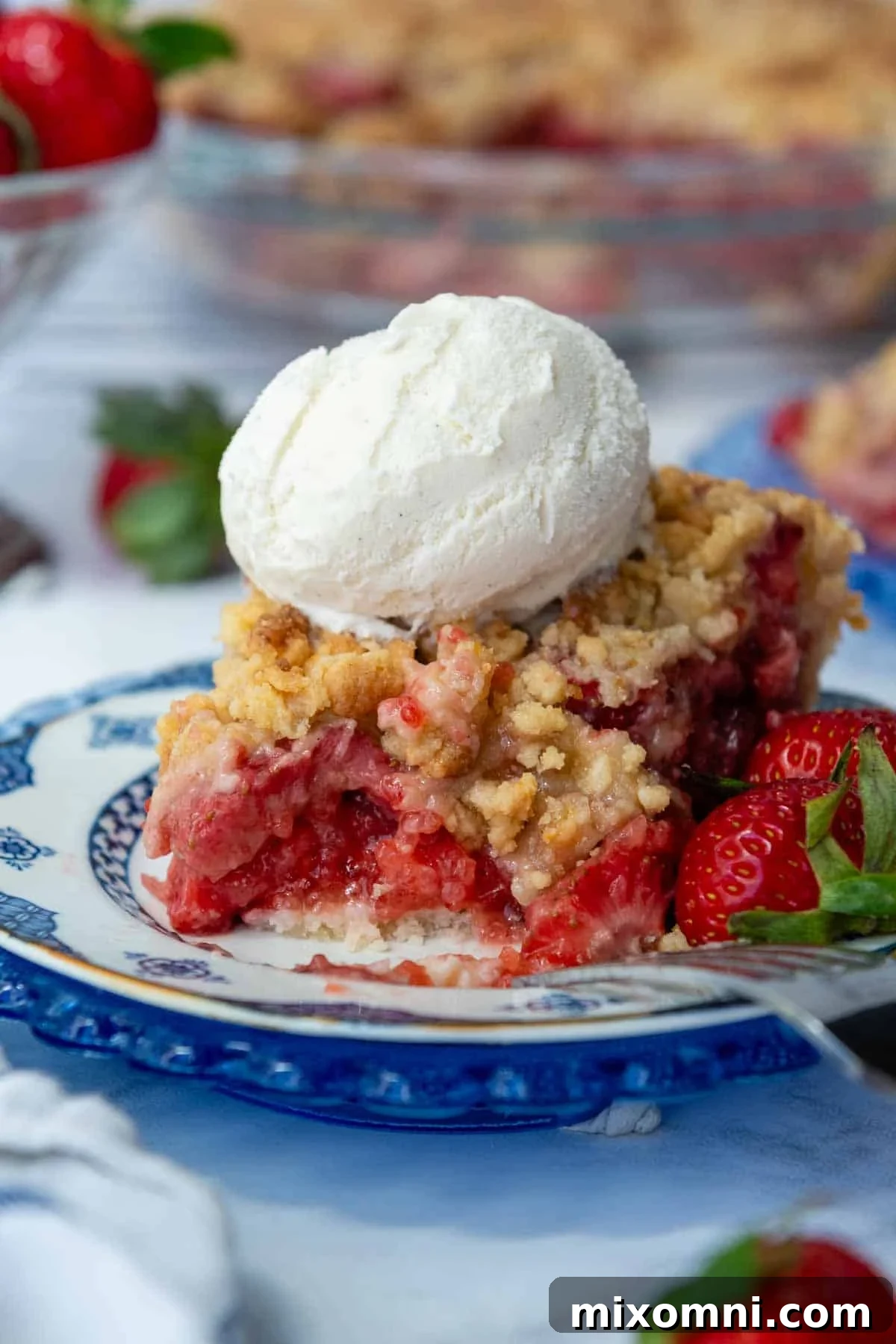 A perfectly baked slice of gluten-free strawberry pie with a scoop of vanilla ice cream melting on top, showing a bite taken out.