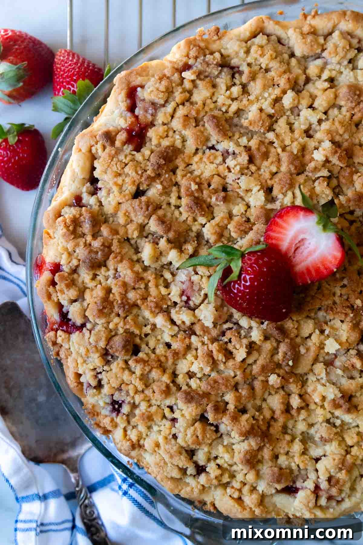 Overhead shot of an unsliced, golden-brown gluten-free strawberry pie cooling on a wire rack.