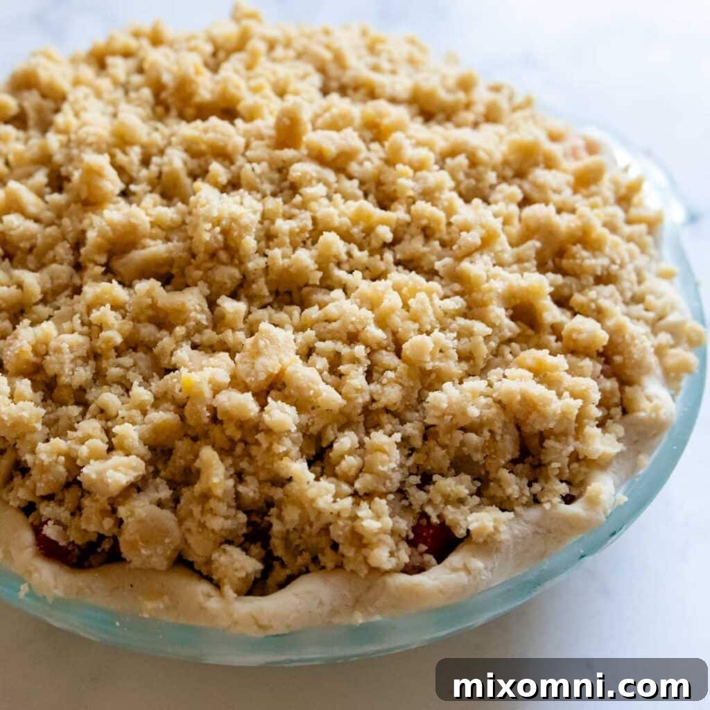 An unbaked strawberry pie in a crust with streusel topping, ready for the oven.