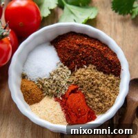 A small white bowl with spices in it and cherry tomatoes next to it.