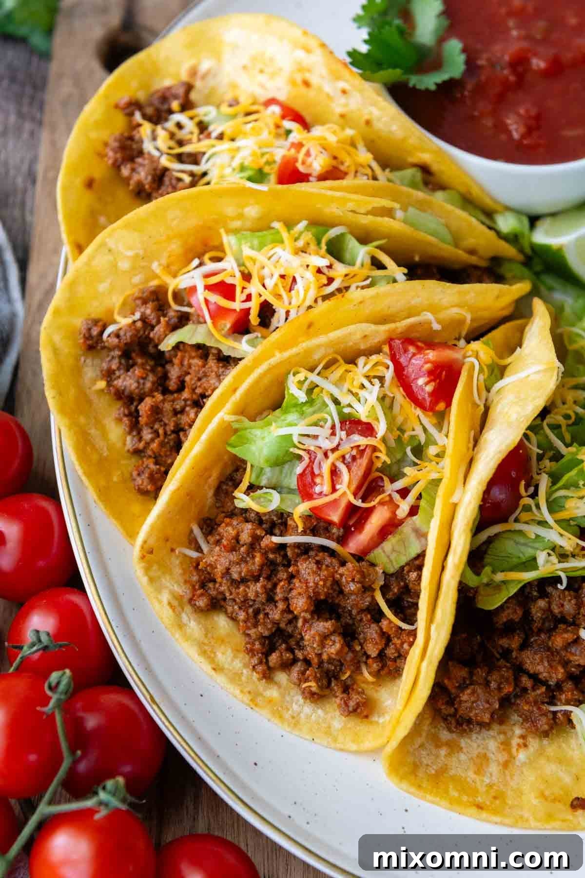A plate of perfectly prepared ground beef tacos on a white plate with fresh salsa in the background, showcasing a delicious gluten-free meal.