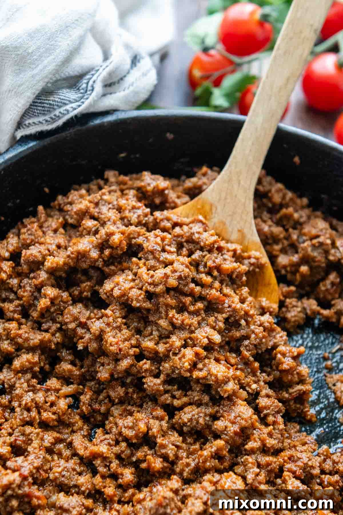 A pan of perfectly cooked gluten-free ground beef taco meat, garnished with fresh cherry tomatoes and ready to be served.
