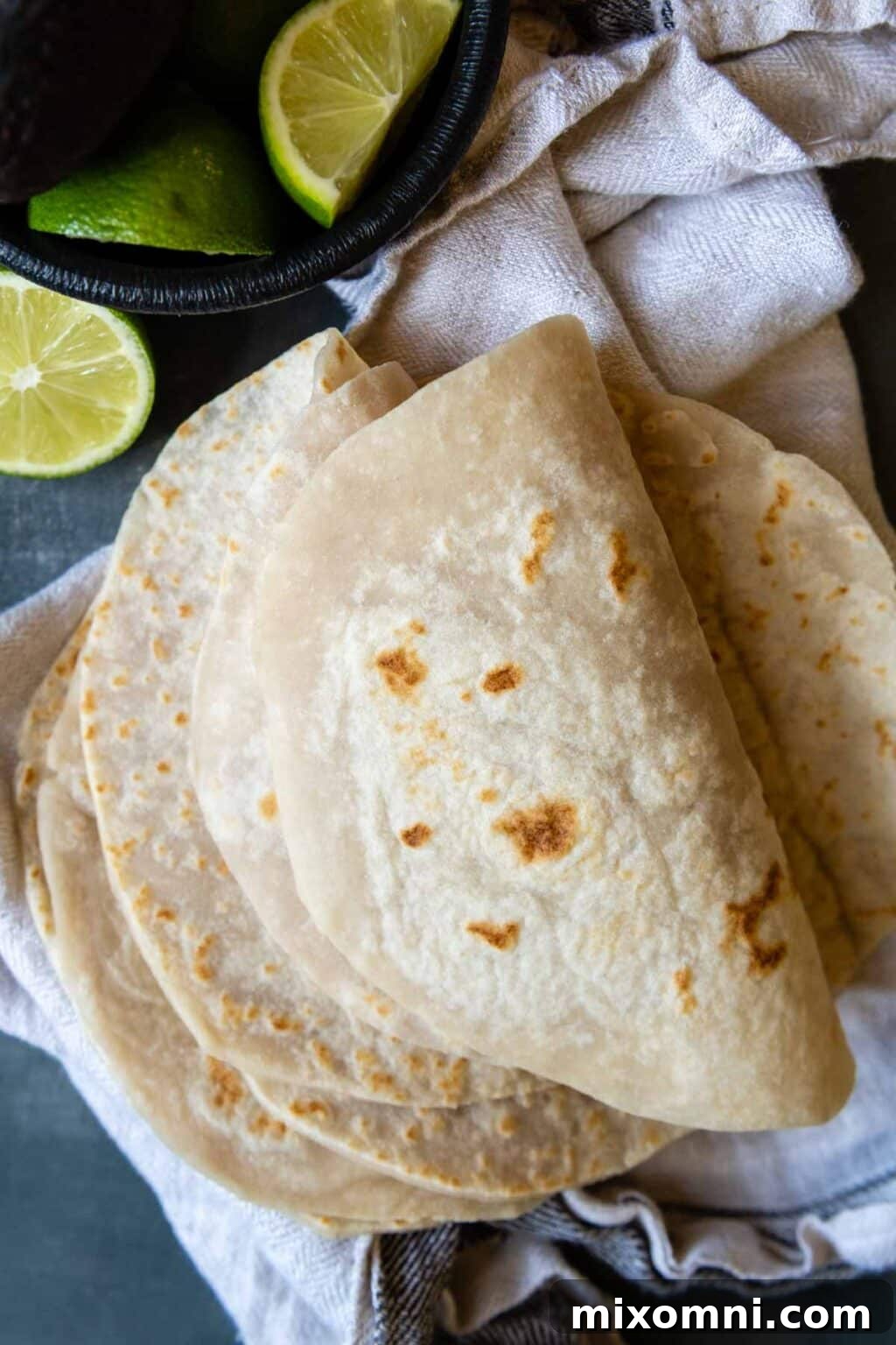 Soft, folded gluten-free flour tortillas arranged with fresh lime slices nearby.