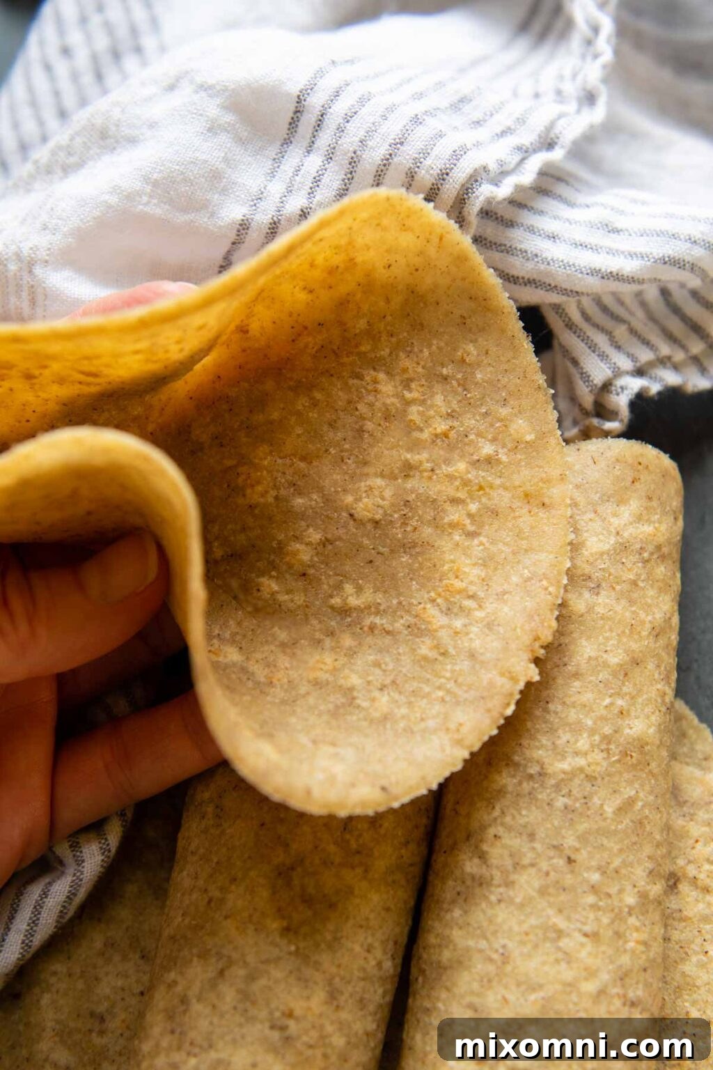 An almond flour tortilla being held up, demonstrating its soft and flexible texture.
