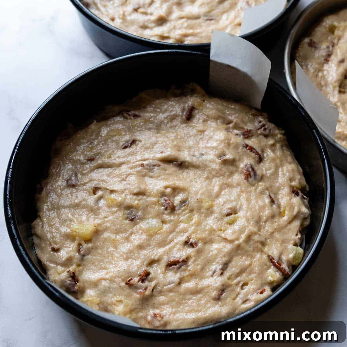 The cake batter evenly spread into three round cake pans, ready for resting and baking.