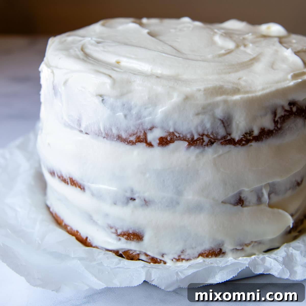A cake with a thin, preliminary crumb coat of frosting applied, ready for chilling.
