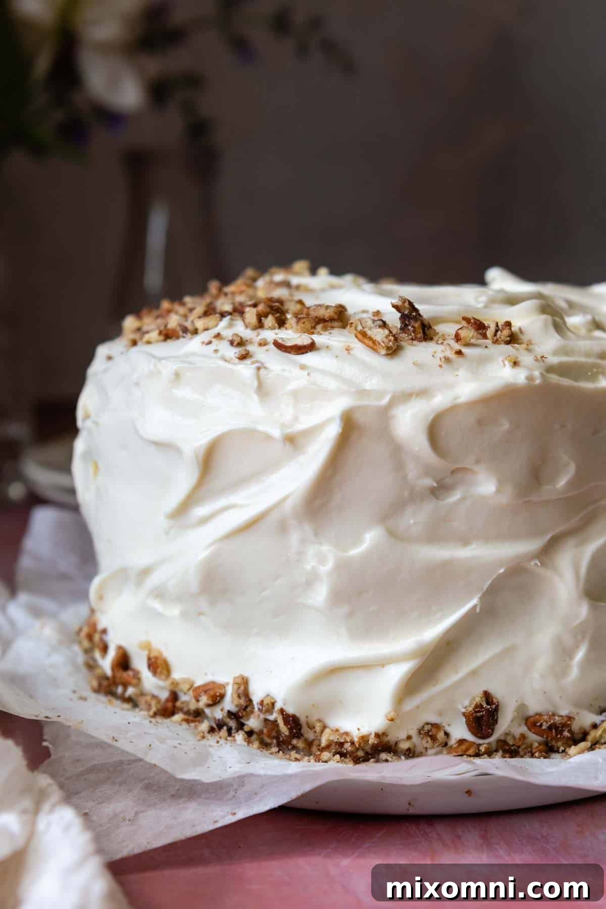 A gorgeously frosted layer cake, adorned with chopped pecans on top and around the edges, ready for serving.