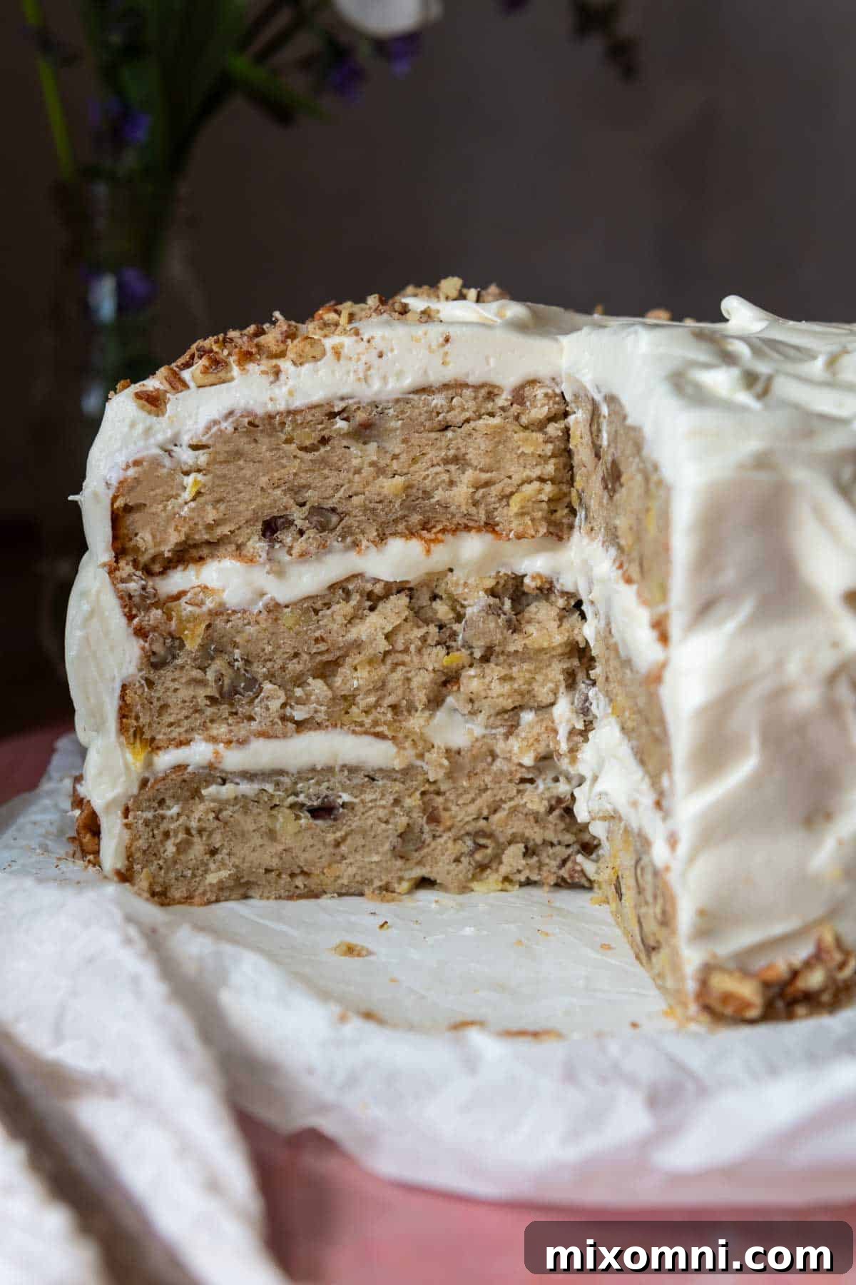 A beautifully presented hummingbird layer cake, sliced open to reveal its moist texture and fruit distribution, resting on a platter.