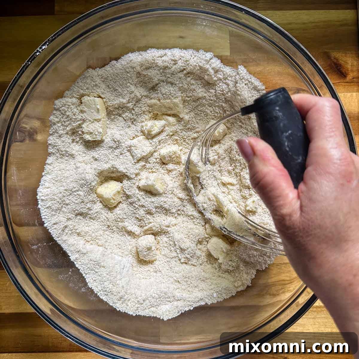 Cold butter being cut into dry ingredients with a pastry blender.
