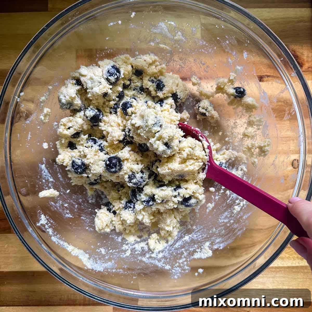 Wet ingredients being stirred into the dry almond flour mixture to form a scone dough.