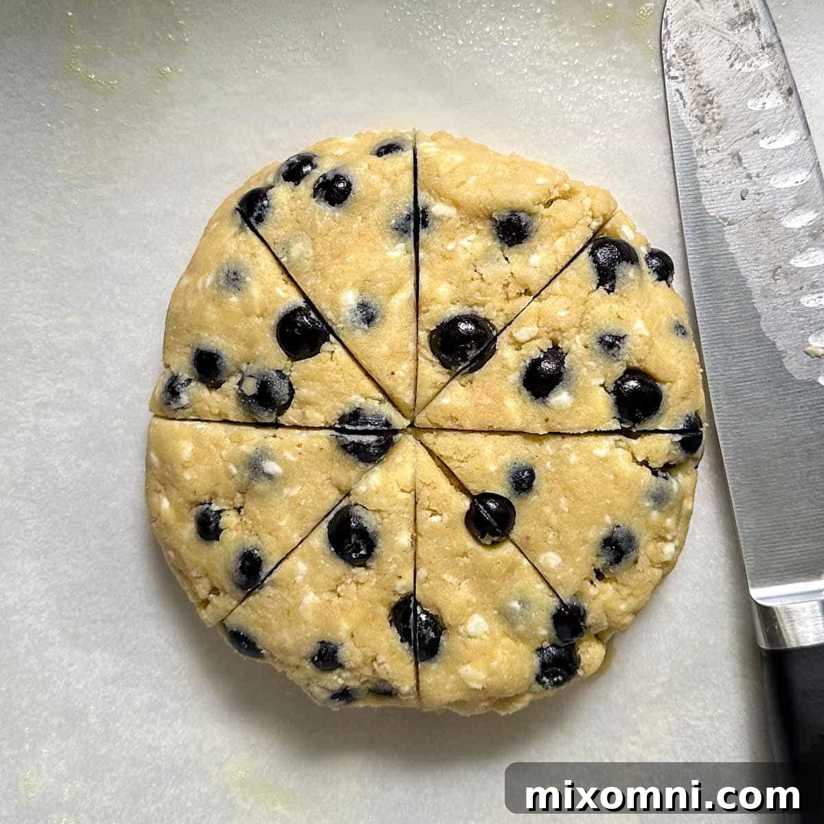 The scone dough shaped into a disk and cut into 8 wedges on a baking sheet.