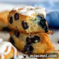 A stack of two scones with the top having a bite taken out and glaze on top.