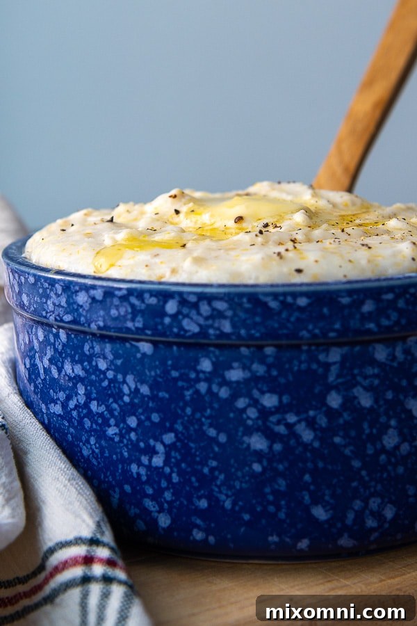 A wooden spoon resting in a bowl of perfectly cooked, creamy grits, with visible steam, ready to be served as a comforting meal.