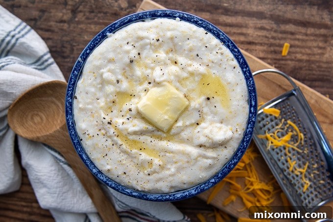 An overhead shot of a blue bowl filled with perfectly cooked, creamy grits, topped with a melting pat of butter, emphasizing its comforting appeal.