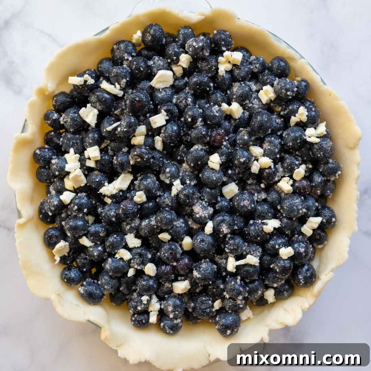 A vibrant blueberry pie filling generously piled into the bottom crust, ready for the lattice topping.