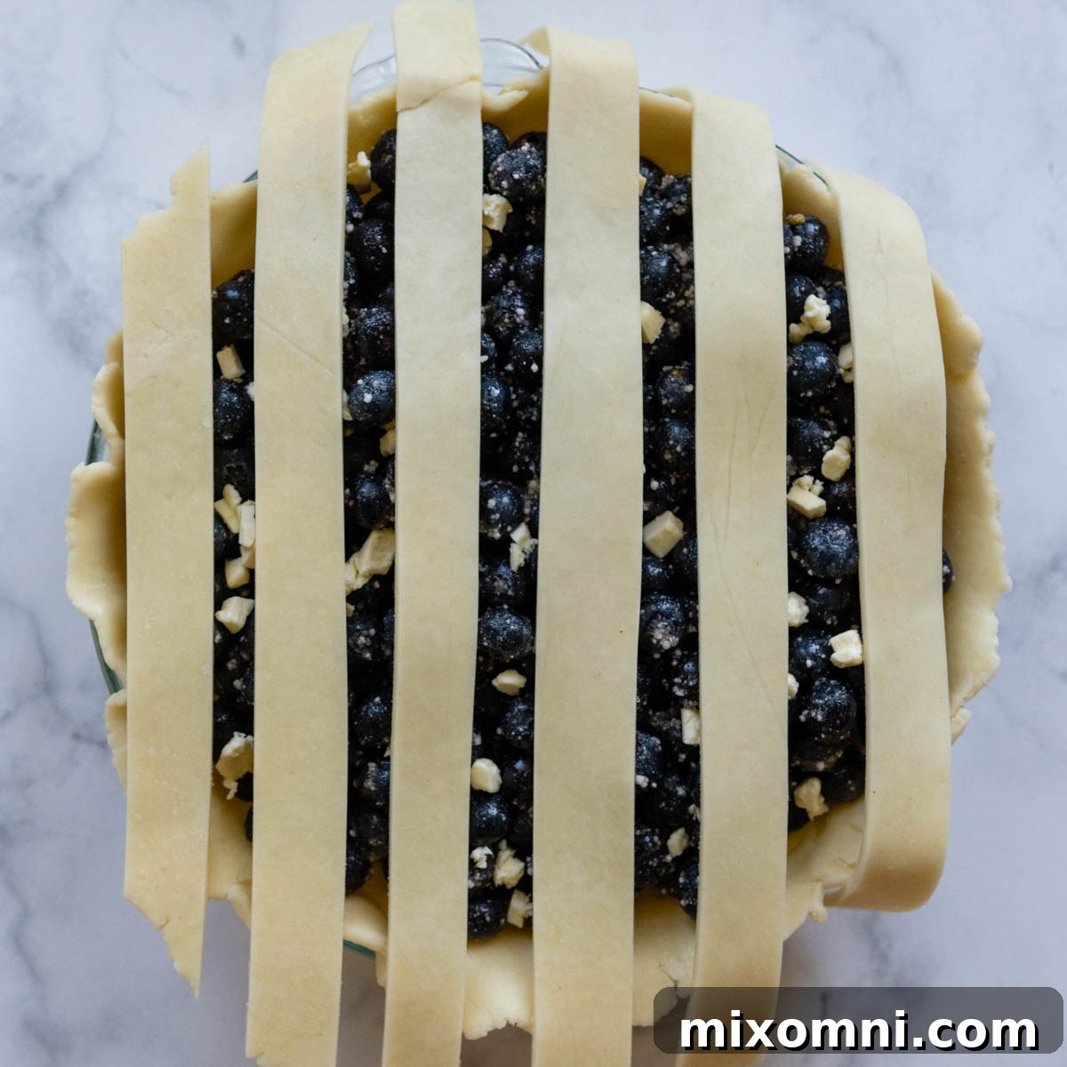 Beginning the lattice weaving process, with vertical strips laid across the pie filling.