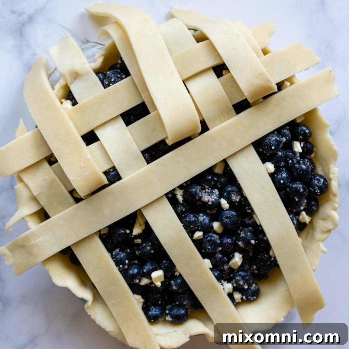 Demonstration of weaving a lattice pie crust, showing how alternating strips are folded back to insert new horizontal strips.