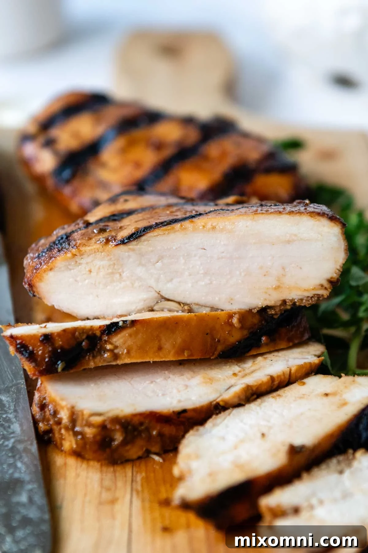 sliced and grilled chicken on a wooden cutting board, facing straight on.