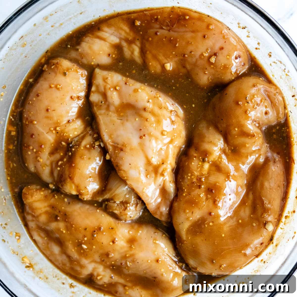 raw chicken breasts marinating in a glass bowl.