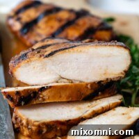 sliced and grilled chicken on a wooden cutting board, facing straight on.