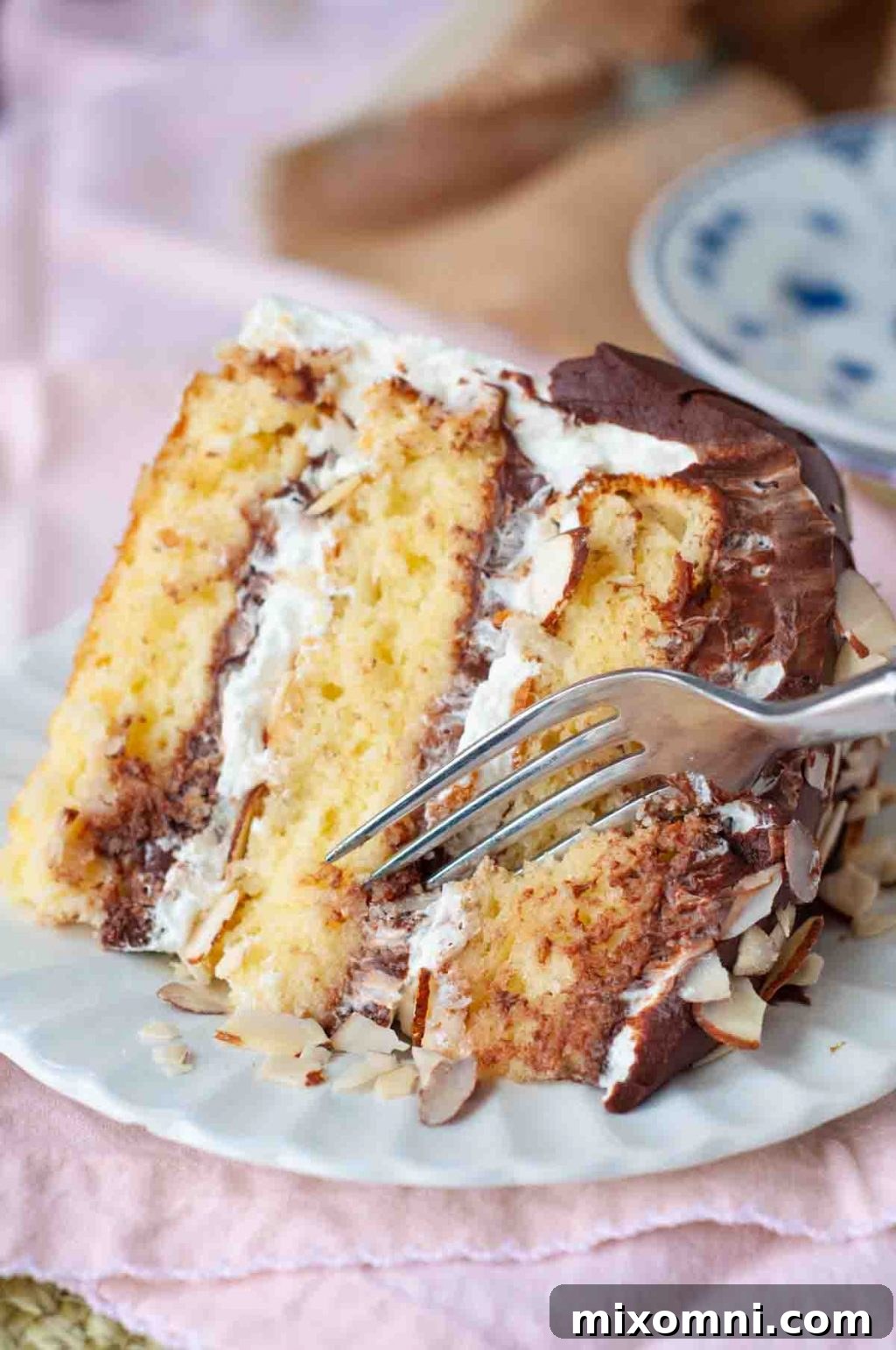 A delectable slice of Almond Joy Cake with a fork poised to take a bite, highlighting its soft texture and inviting layers.