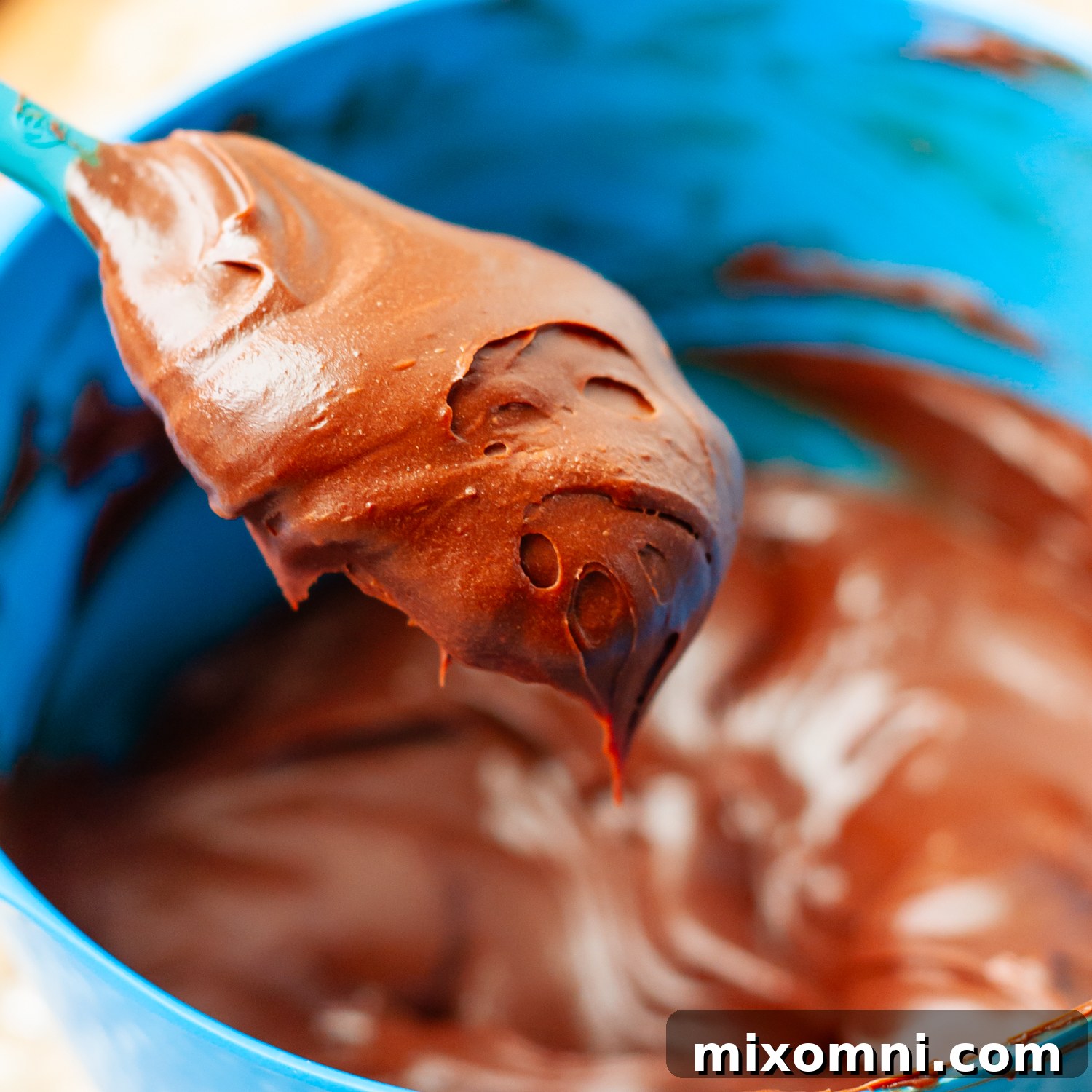 Thickened chocolate ganache ready for spreading, shown on a spoon.