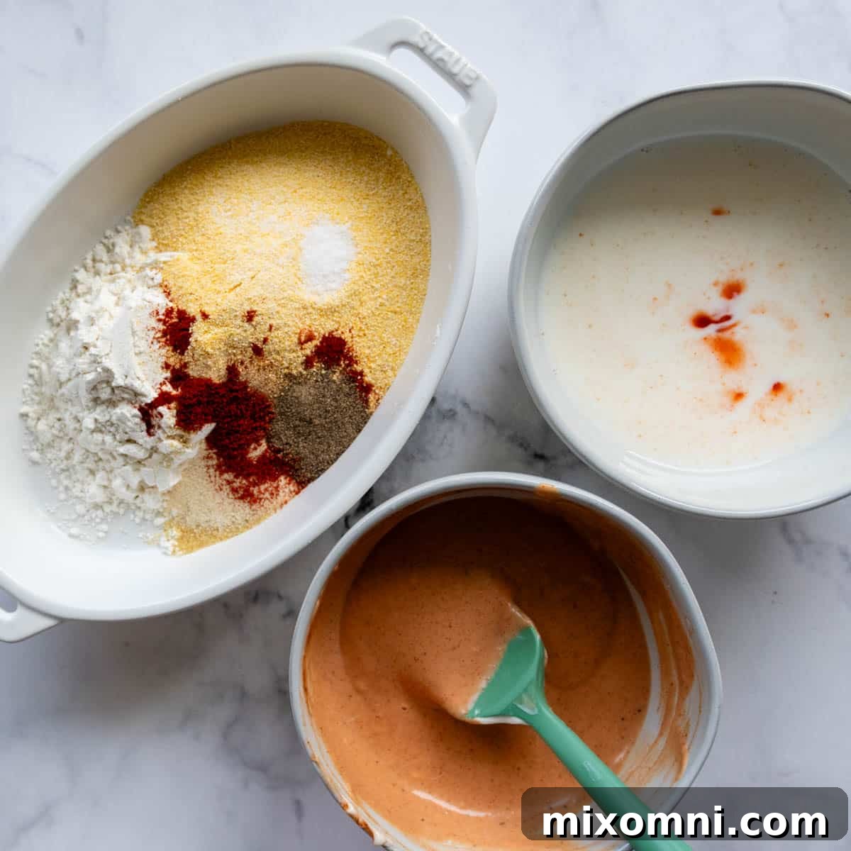 A shallow bowl holding the seasoned gluten-free cornmeal breading mixture, ready for coating the tomatoes.