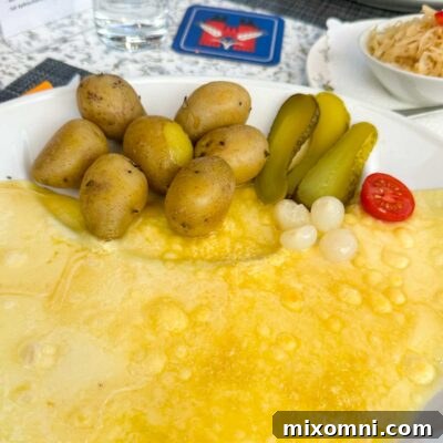 Traditional Swiss Raclette, featuring melted cheese served with boiled potatoes and pickles, a naturally gluten-free delight.