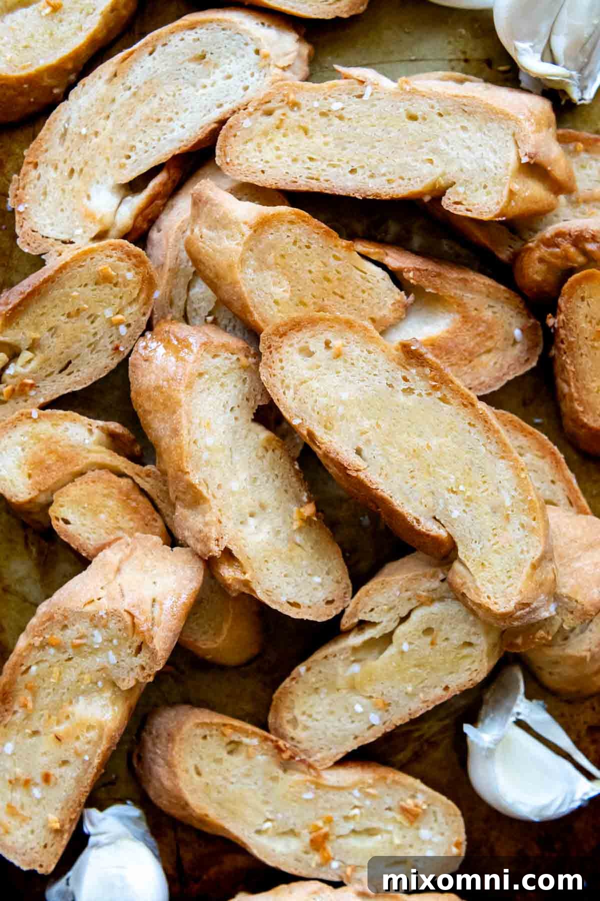 Overhead shot of gluten-free crostini with fresh garlic cloves scattered around, highlighting their golden crispness.