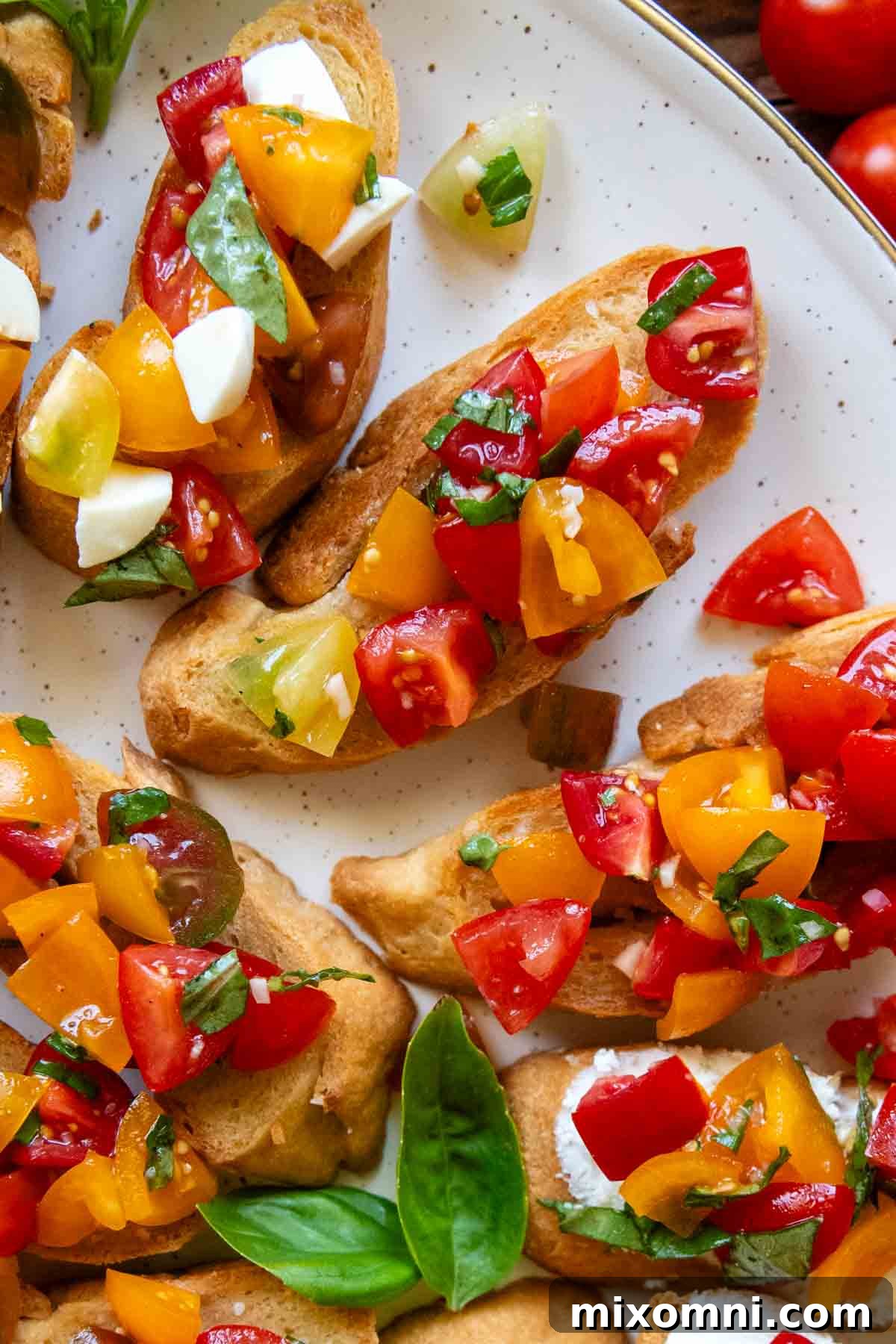 close up of a white platter with various types of bruschetta, some with cheese and some without.