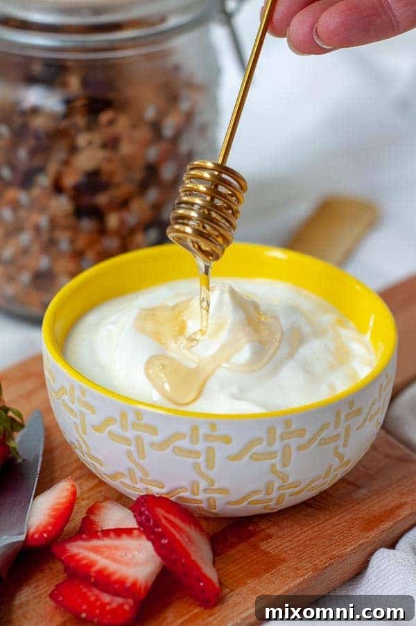 A honey spoon beautifully drizzling golden honey over a pristine bowl of homemade Instant Pot yogurt, ready to be enjoyed.