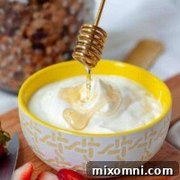 A honey spoon drizzling over a bowl of homemade instant pot yogurt