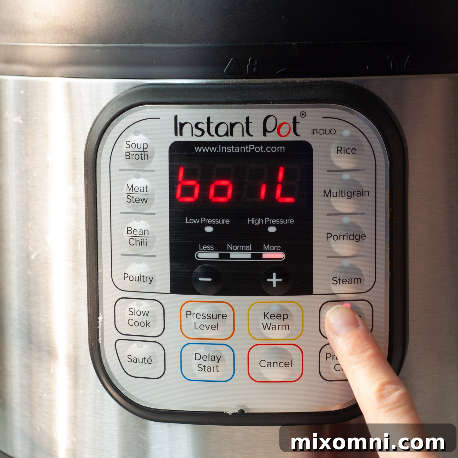 A finger pressing the 'Yogurt' button on an Instant Pot, with 'Boil' displayed on the screen.