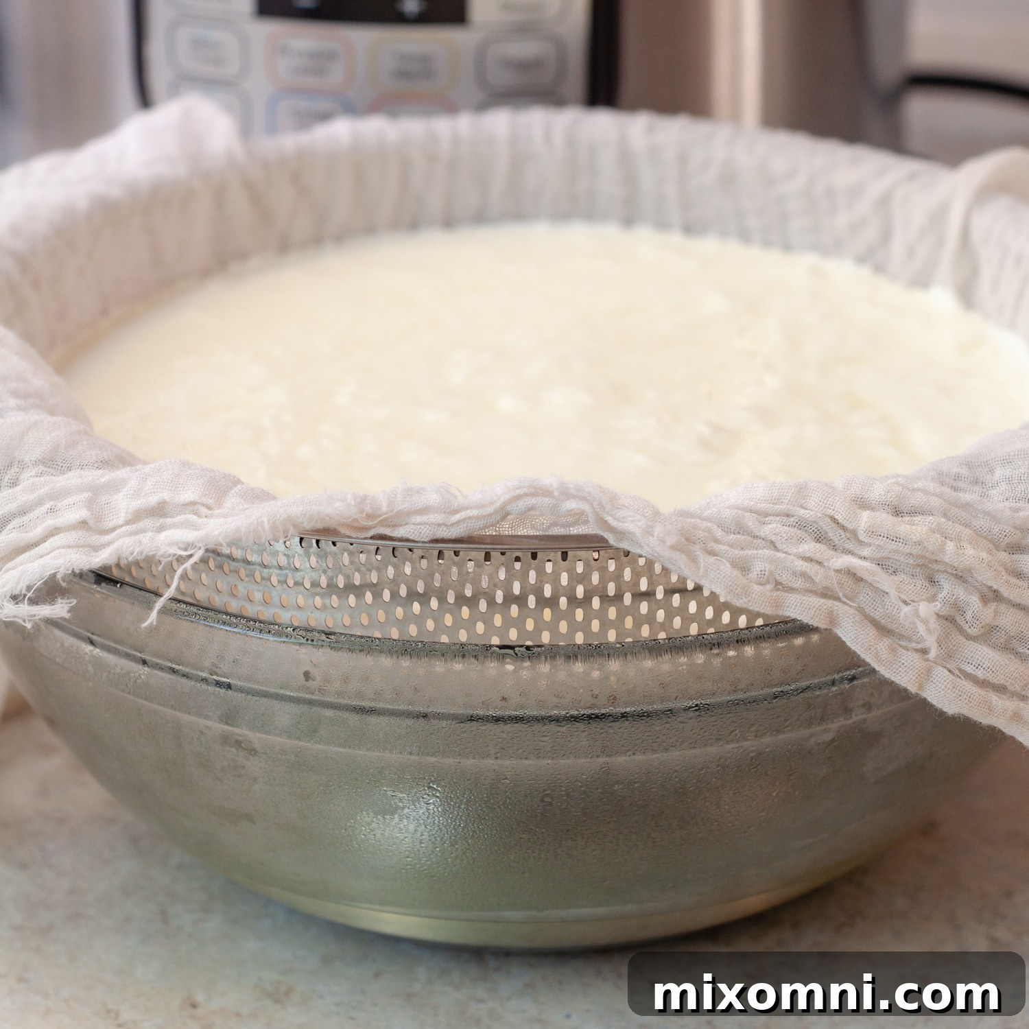 The process of straining homemade yogurt using a cheesecloth-lined colander over a bowl to separate the whey.
