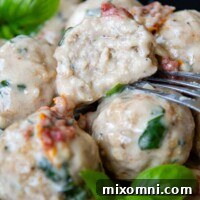 A meatball cut in half with a fork resting next to it, showcasing the moist interior.